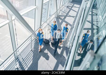 Personale di cabina premuroso che tira le valigie in aeroporto Foto Stock