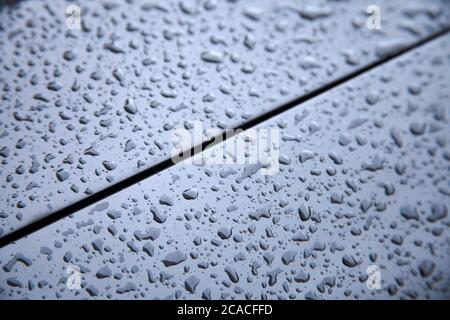 Le gocce d'acqua si raccolgono sulla superficie metallica dell'auto Foto Stock