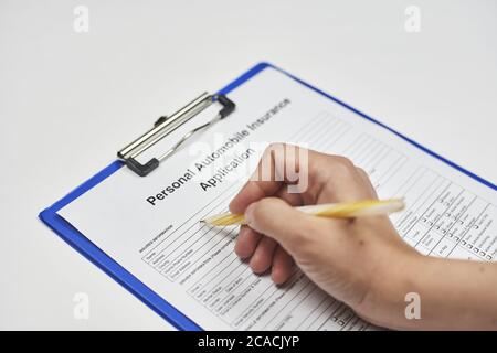 Mano di una persona che compila una domanda di assicurazione sanitaria Foto Stock