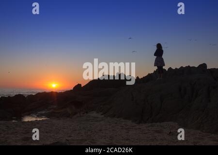 Splendida vista al tramonto sull'oceano dalla costa di Milnerton Beach con amici e familiari che si divertono sulla spiaggia, Città del Capo, Sud Africa Foto Stock
