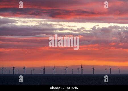 Nuvole colorate insieme alla fattoria eolica in mare aperto. Foto Stock