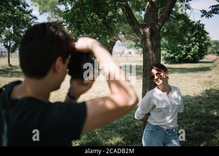 Retro dell'uomo che scatta le foto di bella donna all'aperto Foto Stock