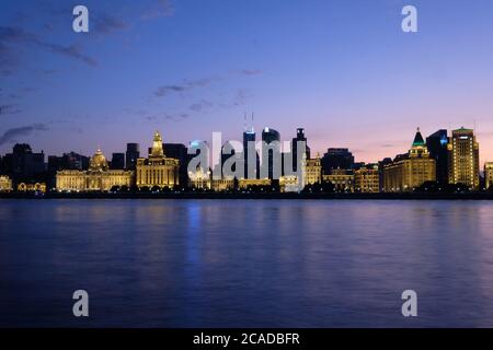 Tramonto blu ora del Bund a Shanghai. Edifici occidentali illuminati d'oro sulle rive del fiume Huangpu. Lungo fiume di esposizione pacifica. Grandangolo Foto Stock