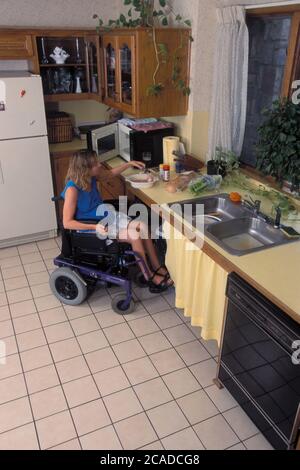 Austin Texas USA, 1996: 40 anni, donna handicappata fa insalata in cucina accessibile con sedia a rotelle. MR MR ET-275-276 ©Bob Daemmric Foto Stock