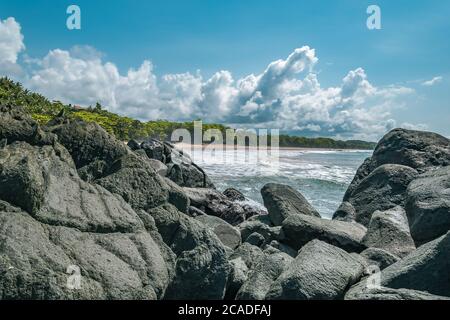 Massi neri bui giacenti su una spiaggia dopo la costa in Axim Ghana Africa occidentale Foto Stock