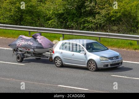 2004 Silver VW Volkswagen Golf GT TDI traino jetskis coperto su rimorchio; veicoli a traffico veicolare in movimento, auto che guidano su strade del Regno Unito, motori, automobilismo sulla rete autostradale M6. Foto Stock