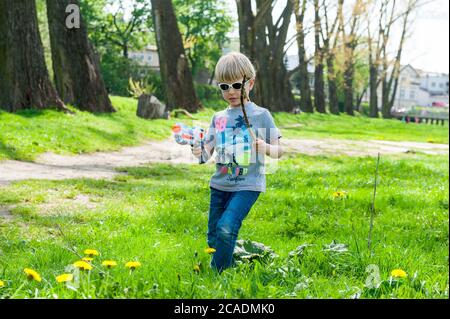 ragazzo di 4 anni che gioca con un bastone e un giocattolo pistola Foto Stock