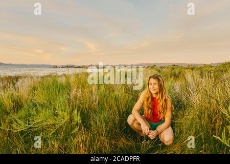 Giovane donna seduta in erba alta vicino al lago Mono nel nord della California. Foto Stock