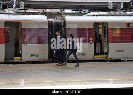 Una coppia dal look elegante che cattura un treno elettrico LNER Azuma Alla stazione di Leeds Foto Stock