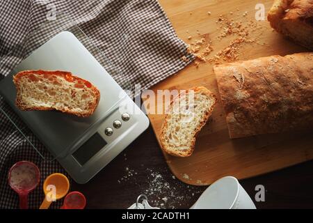 Affettato il pane con la bilancia e misurini su legno tabella Foto Stock