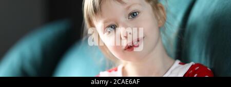 Bambina seduta in divano a casa con banca piggy Foto Stock