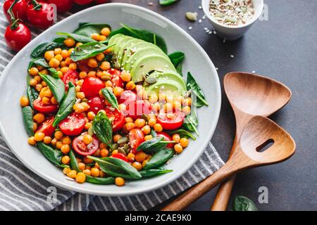 Insalata fresca e salutare con ceci, avocado, pomodori ciliegini e spinaci. Foto Stock