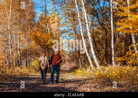 Passeggiata d'autunno. Coppia senior passeggiate nel parco di caduta. Felice l'uomo e donna che parlano e relax all'aperto Foto Stock