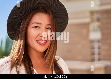 Ritratto di felice sorridente ragazza asiatica con bretelle dentali e cappello Foto Stock