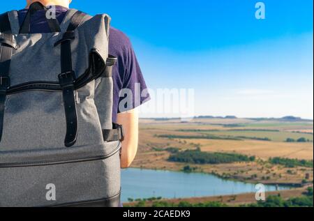 Zaino da primo piano sul retro degli uomini che viaggiano guardando l'orizzonte sotto un cielo blu. Foto Stock