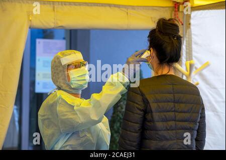 Avviso pandemico Covid-19. Tenda di campo dell'ospedale di Triage per il primo SOCCORSO per il paziente infettato con il virus di corona. Medico con controlli la febbre del paziente. Foto Stock