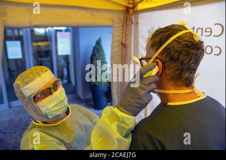 Avviso pandemico Covid-19. Tenda di campo dell'ospedale di Triage per il primo SOCCORSO per il paziente infettato con il virus di corona. Medico con controlli la febbre del paziente. Foto Stock