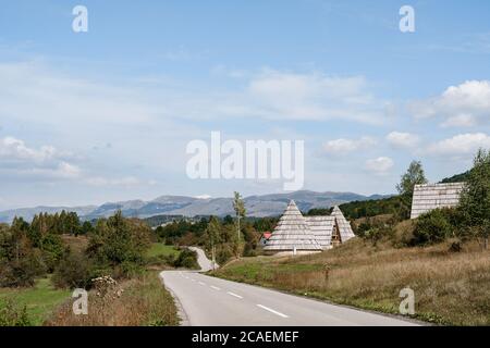 Strada asfaltata con segnaletica stradale in una pittoresca area montagnosa attraverso il settore privato e la foresta. Foto Stock