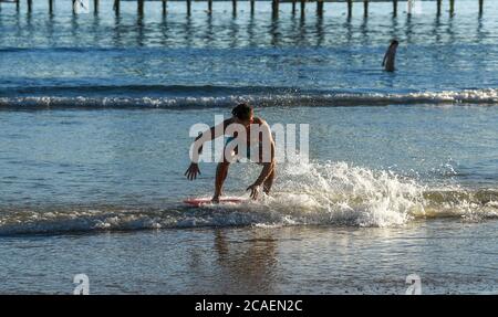Brighton UK 6 agosto 2020 - questo giovane uomo ama scivolare in mare sulla spiaggia di Brighton in una bella serata di sole come si prevede che le temperature raggiungeranno di nuovo al di sopra di 30 gradi nel Sud Est di domani : Credit Simon Dack / Alamy Live News Foto Stock