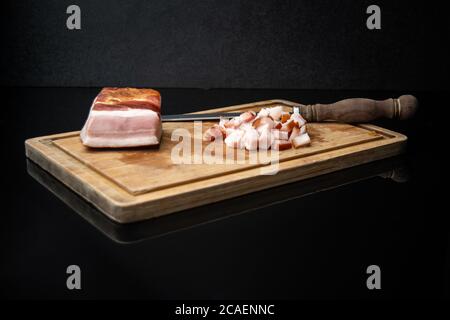 pancetta affumicata su un tagliere su un tavolo di vetro nero Foto Stock