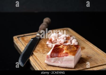 pancetta affumicata su un tagliere su un tavolo di vetro nero Foto Stock