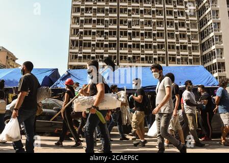 Beirut, Libano. 6 agosto 2020. Giovani libanesi camminano oltre l'edificio fortemente danneggiato Electricite du Liban con scopa e picche, determinato a ripulire dopo una catastrofica esplosione nella zona portuale che ha causato più di 150 vite, ferito oltre 5000 persone e devastato gran parte della città. Credit: Elizabeth Fitt/Alamy Live News Foto Stock