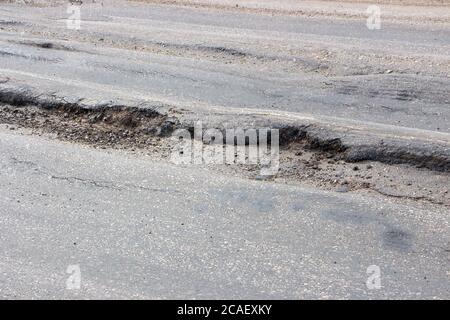 Postolo sulla strada da autocarri pesanti. Distruzione di asfalto da auto sovraccaricate. Foto Stock