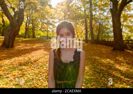 Giovane bella donna asiatica con alberi d'autunno scenici nella foresta Foto Stock