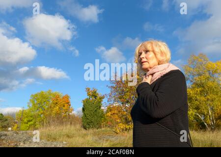 Basso angolo di donna anziana che guarda la distanza sulla montagna Foto Stock