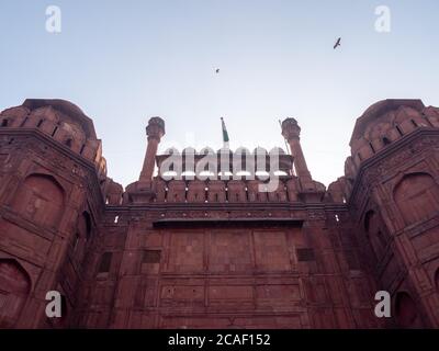 una vista ad angolo basso della bandiera indiana che vola sopra il cancello di lahori al forte rosso nella vecchia delhi Foto Stock