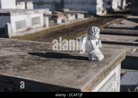 Piccola statua bianca di un angelo in preghiera su una lapide nel cimitero Foto Stock