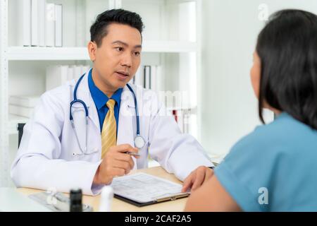 L'uomo asiatico medico e paziente di donna stanno discutendo la consultazione circa la diagnosi di problema di sintomo della malattia parlano con il paziente circa il farmaco e tre Foto Stock
