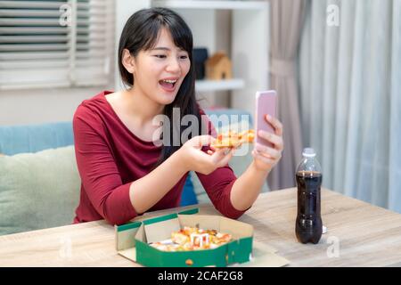 Donna asiatica virtuale happy hour incontro cena e mangiare cibo pizza online insieme al suo ragazzo in videoconferenza con tablet digitale per uno o Foto Stock