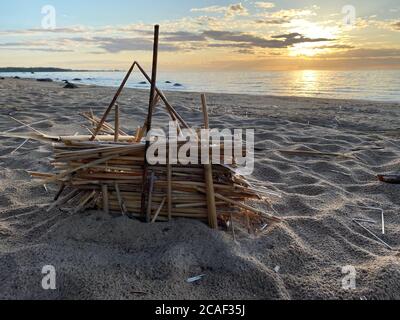 piccola capanna fatta di paglia sulla sabbia dal mare al tramonto Foto Stock