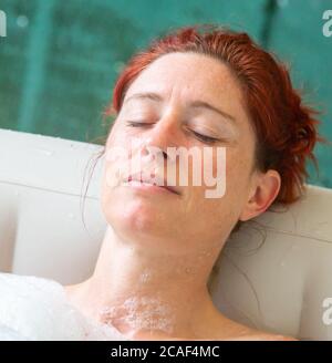 Ritratto di Pretty naturale rosso donna rilassante nella sua jacuzzi Foto Stock