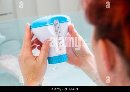 Donna decapitata in un bagno di vasca calda che controlla la temperatura dell'acqua Foto Stock