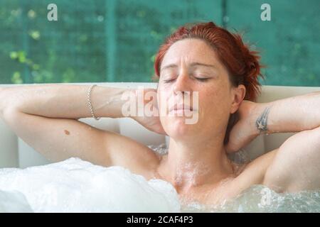 Ritratto di Pretty naturale rosso donna rilassante nella sua jacuzzi Foto Stock