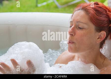 Ritratto di Pretty naturale rosso donna rilassante nella sua jacuzzi Foto Stock