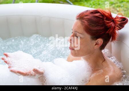 Ritratto di Pretty naturale rosso donna rilassante nella sua jacuzzi Foto Stock