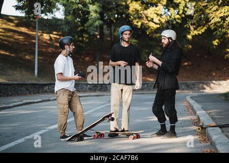 Tre ragazzi parlano di skateboard. Foto Stock