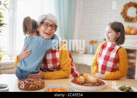 Buon giorno del Ringraziamento! Festa d'autunno. Famiglia seduta al tavolo e festeggiando la vacanza. Cena tradizionale. Nonna e nipote. Foto Stock