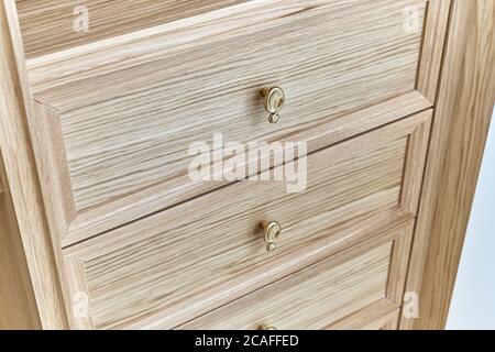 Cassetti in legno con manici dorati da vicino. Ripieno di legno di guardaroba. armadio in legno con ante laccate bianche Foto Stock