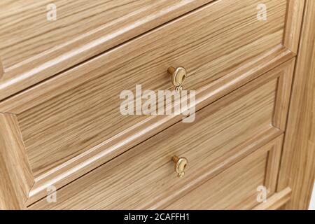 Cassetti in legno con manici dorati da vicino. Ripieno di legno di guardaroba. armadio in legno con ante laccate bianche Foto Stock