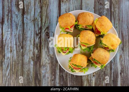 Piccoli panini con prosciutto e verdure sul piatto su un tavolo di legno. Foto Stock