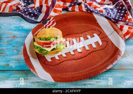Sandwich su piatto da calcio americano con bandiera americana su sfondo di legno. Foto Stock