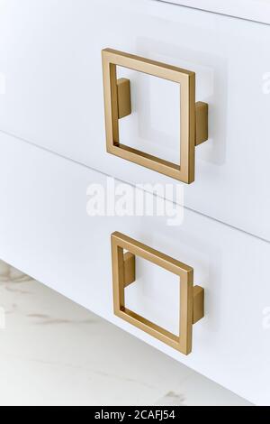 Maniglie quadrate in oro su porte di un mobile lucido di vanity bagno. Primo piano Foto Stock