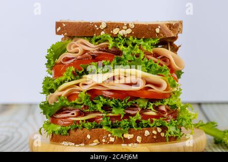 Delizioso sandwich con prosciutto e verdure su tavolo di legno. Foto Stock