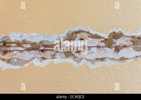 Riparazione incrinature del cordone di giunzione a secco in corso. Area danneggiata scavata. Giunto a secco esposto con unghie arrugginite. Foto Stock