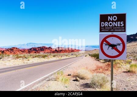 Nessun segnale di avvertimento per la zona dei droni vieta il lancio, l'atterraggio o il funzionamento di aeromobili non presidiati. Strada solitaria, scenografiche formazioni di arenaria rossa, e dese Foto Stock