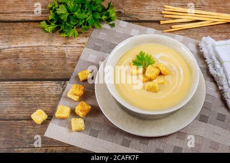 Deliziosa zuppa cremosa di pollo con crostini e bastoncini di pane italiani su un tavolo di legno. Foto Stock